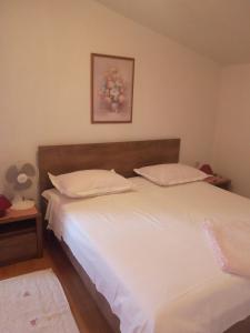 a bedroom with a bed with white sheets and pillows at Apartment House Aria in Baška Voda