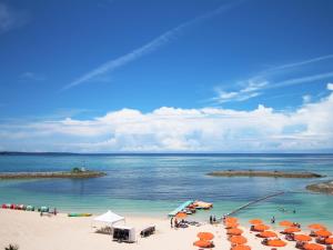 a beach with umbrellas and people in the water at Sheraton Okinawa Sunmarina Resort in Onna