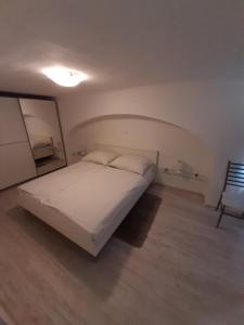 a bedroom with a white bed and a chair at Apartment Osk in Osijek