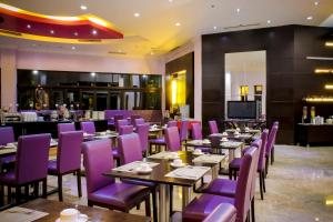 ein Restaurant mit lila Stühlen und Tischen und einer Bar in der Unterkunft Zurich Hotel Balikpapan in Balikpapan