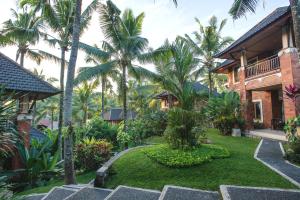 un jardin avec des palmiers et un bâtiment dans l'établissement Rama Phala Resort & Spa, à Ubud