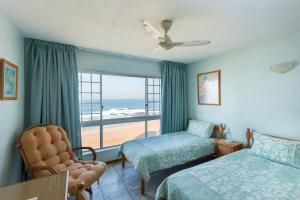 een slaapkamer met 2 bedden en een raam met uitzicht op het strand bij Kenwyn on Sea 305 in Ballito