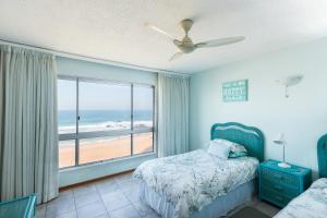 een slaapkamer met een bed en uitzicht op het strand bij Kenwyn on Sea 305 in Ballito