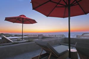 une terrasse avec des canapés, un parasol et un coucher de soleil dans l'établissement Andronikos Canaves, à Oia