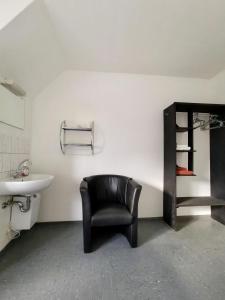 a bathroom with a black chair and a sink at Pension Akropolis in Rellingen