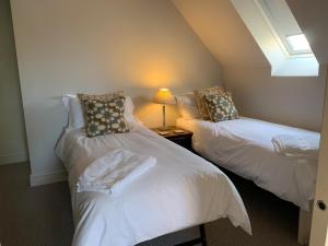 two twin beds in a room with a window at The Bothy in Pewsey