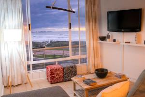 a living room with a large window with a view of the ocean at Lagoon Beach Neptune Isle Cape Town in Cape Town