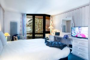 a bedroom with a large bed and a television at Lake Hotel Courchevel 1850 in Courchevel