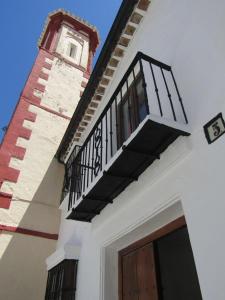 Edificio blanco con balcón y torre del reloj en La Casa 5, en Grazalema