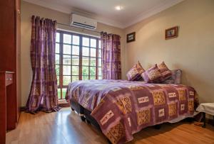 a bedroom with a bed and a large window at Ekhaya Guest House in Ballito
