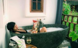 a woman sitting in a bath tub reading a book at Rambutan Resort – Siem Reap in Siem Reap
