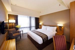 una camera d'albergo con un grande letto e una sedia di Fullon Hotel Hualien a Città di Hualien