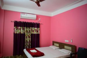 1 dormitorio con paredes rosas y 1 cama con cortina en Jupiter Lodge, en Siliguri