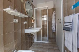 een badkamer met een wastafel, een toilet en een spiegel bij Albergo Aurora in Malcesine