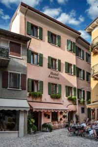 a building with green shutters and people sitting at tables at Albergo Aurora in Malcesine