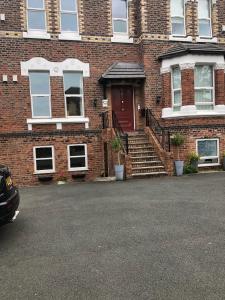 a brick house with a red door and stairs at Just by the Gormly MenAnother Place Near Liverpool 13 Abbortford Road Crosby Liverpool L23 6ux in Crosby