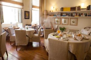 Una donna sta in piedi in una sala da pranzo con tavoli di Xenon Apollonos a Ermoupoli