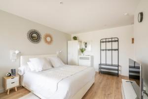 Dormitorio blanco con cama blanca y espejo en Studio Confort O NICO-Dormiratoulouse Colomiers, en Colomiers