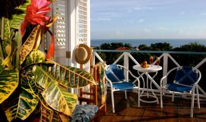 a balcony with a table and chairs and the ocean at Hotel Mockingbird Hill in Port Antonio