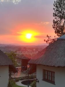 a sunset with the sun setting behind two buildings at Buller's Rest Guest Lodge in Ladysmith