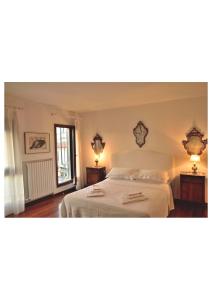 een slaapkamer met een wit bed en 2 lampen bij Mimi's loft in Venetië