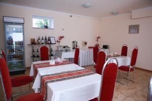 a dining room with white tables and red chairs at Ossanna Hotel in Yerevan