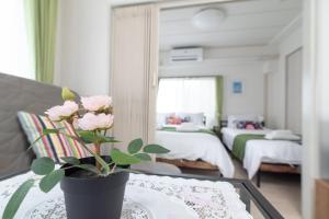 a room with a table with a vase with pink roses at Uhome Iriya Apartment in Tokyo