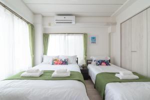 a bedroom with two beds with green and white sheets at Uhome Iriya Apartment in Tokyo