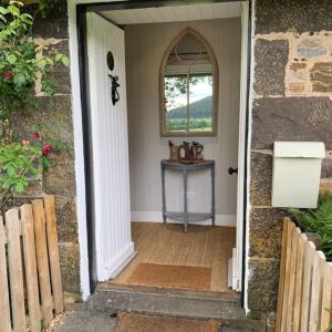 an open door to a house with a table at Glencroft A Fairytale Highland Cottage in Aberfeldy