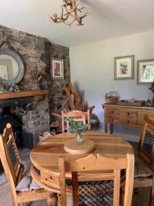 a dining room with a wooden table and a fireplace at Glencroft A Fairytale Highland Cottage in Aberfeldy