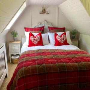 - un lit rouge et blanc avec des oreillers rouges dans l'établissement Glencroft A Fairytale Highland Cottage, à Aberfeldy