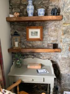 a stone wall with shelves and a white table at Glencroft A Fairytale Highland Cottage in Aberfeldy