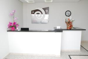 a reception desk with two flowers and a clock at Monte Castro Executive Hotel in Araguari
