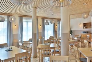 a restaurant with wooden tables and chairs and chandeliers at JUFA Hotel Pöllau in Pöllau