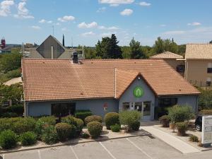 een gebouw met een verzakt dak met een groen bord erop bij Campanile Salon-De-Provence in Salon-de-Provence