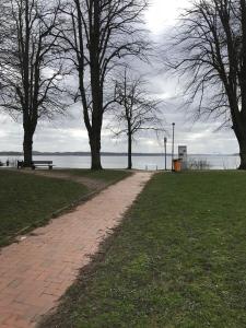 a brick path in a park with trees and the water at 1 Zimmer Wohnung in Strand nähe in Kiel +3 photos
