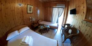ein Schlafzimmer mit einem weißen Bett in einem Holzzimmer in der Unterkunft Balogiannis Hotel in Paralia Pantaleimonos