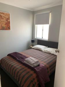 1 dormitorio con 1 cama con manta y ventana en Cozy 3BR Townhouse in Liverpool CBD with parking, en Liverpool