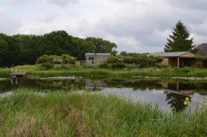 a small pond with a house in the background at Rose Shepherds Hut in Badlesmere