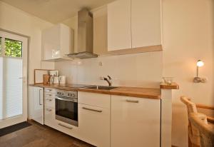 a kitchen with white cabinets and a sink at Ferienhäuser Südwind in Hiddensee