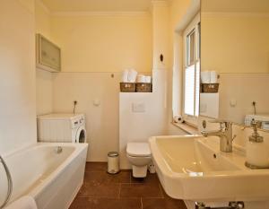 a bathroom with a tub and a toilet and a sink at Ferienhäuser Südwind in Hiddensee