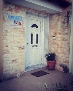 una puerta blanca en una pared de ladrillo con una maceta en Matina's Apartments en Prinos