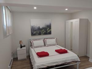 Un dormitorio blanco con una cama grande con almohadas rojas en Spacious basement one bedroom apartment, WiFi. en Montreal