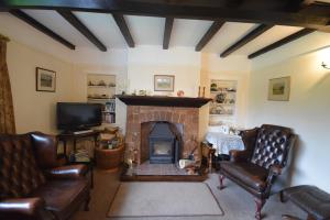 a living room with leather chairs and a fireplace at Bournestream in Withycombe