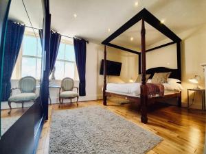a bedroom with a canopy bed and two chairs at The Old Lodge in Stroud