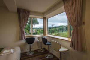 a room with two chairs and a large window at Ritz Garden Niji in Biei