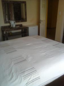 a large white bed in a room with a table at Koiketla Guesthouse in Pretoria