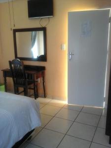 a bedroom with a door and a chair and a table at Koiketla Guesthouse in Pretoria