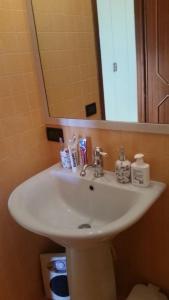 Un lavabo blanco en un baño con espejo. en Villa Capitolo, en Monopoli