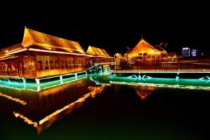 un grupo de edificios con luces en el agua por la noche en Xishuangbanna Elephant Home Guesthouse, en Jinghong